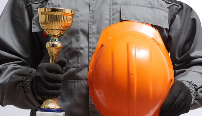 Man in coveralls holding a trophy and a hard hat