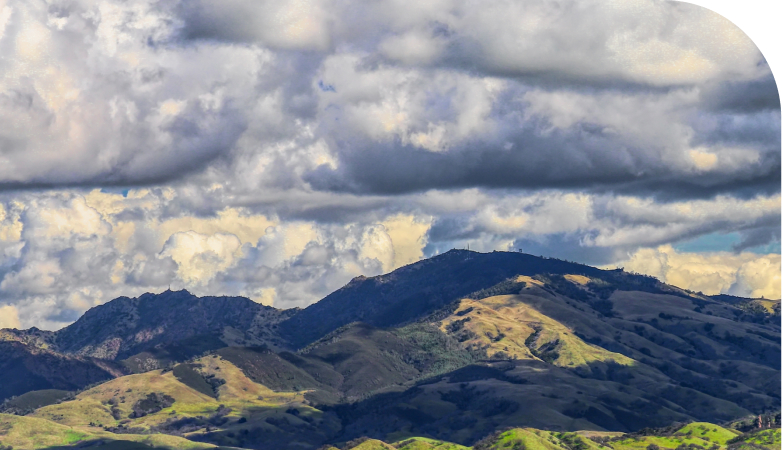 Green mountains beneath clouds and sky