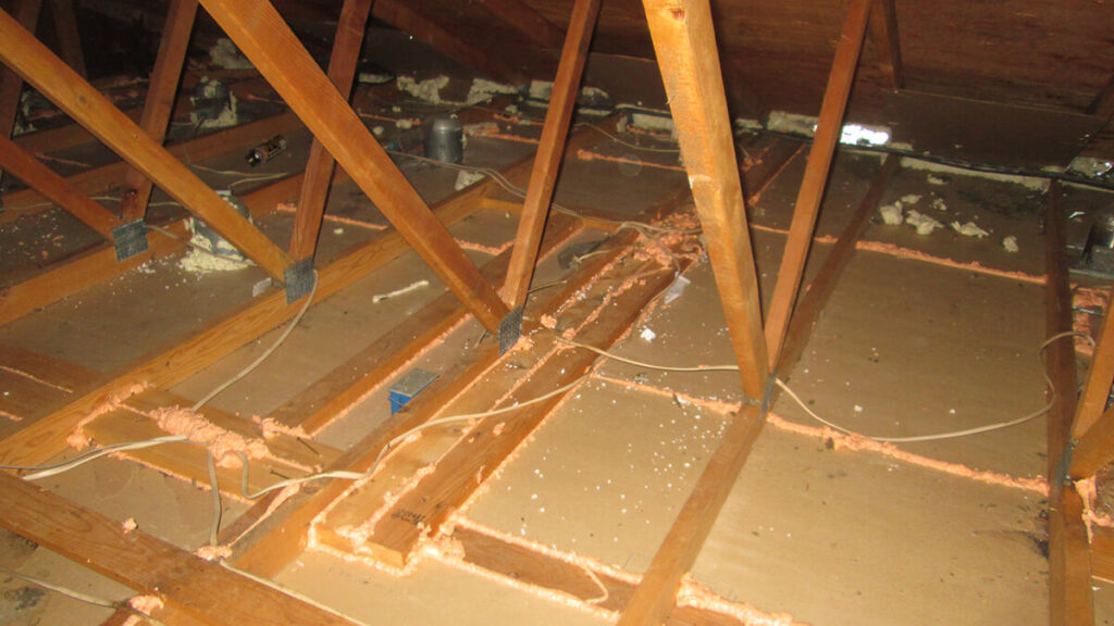 An attic with sealant between sheetrock and trusses