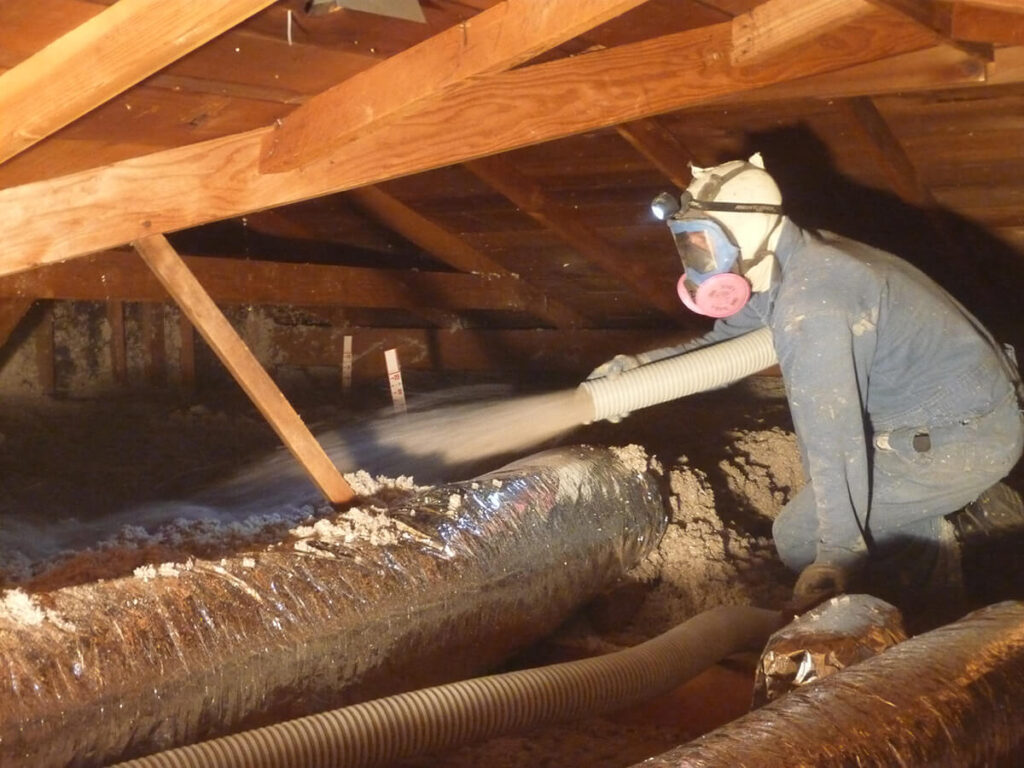 Technician blowing cellulose insulation into an attic