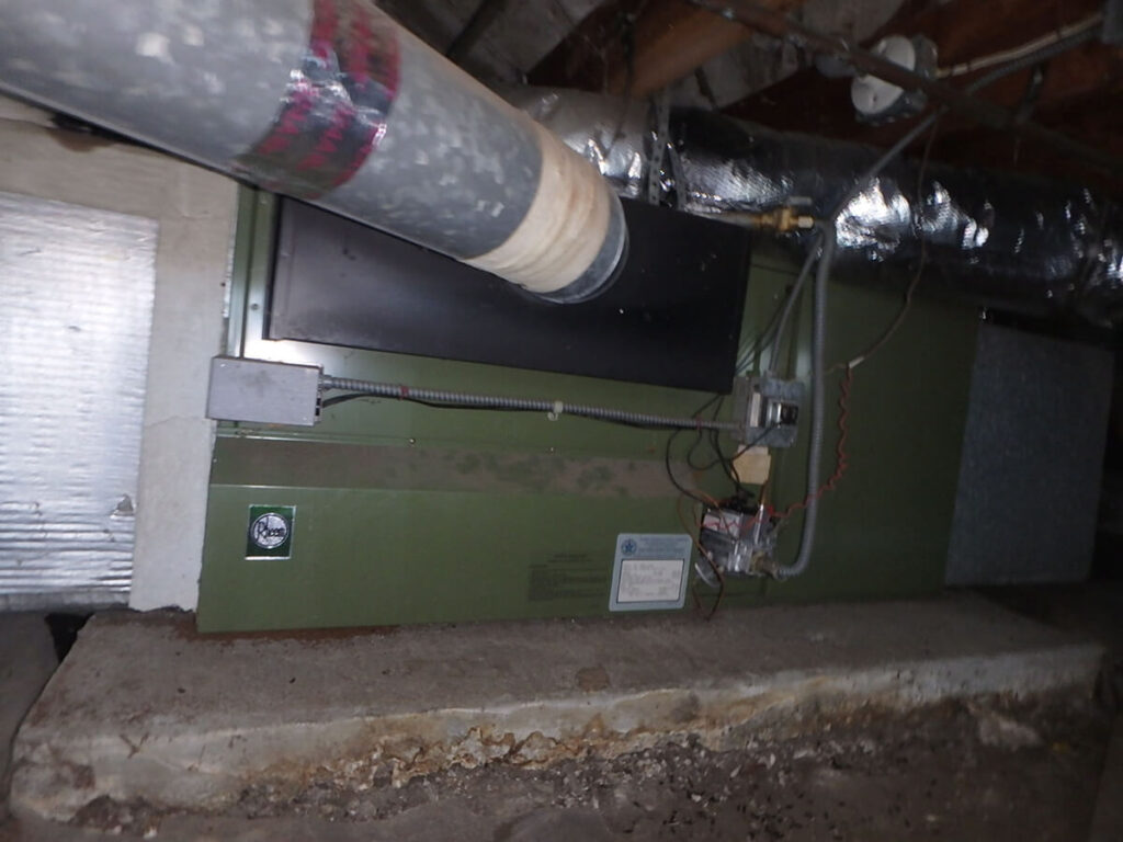 Photo of a crawlspace showing an outdated and wasteful furnace